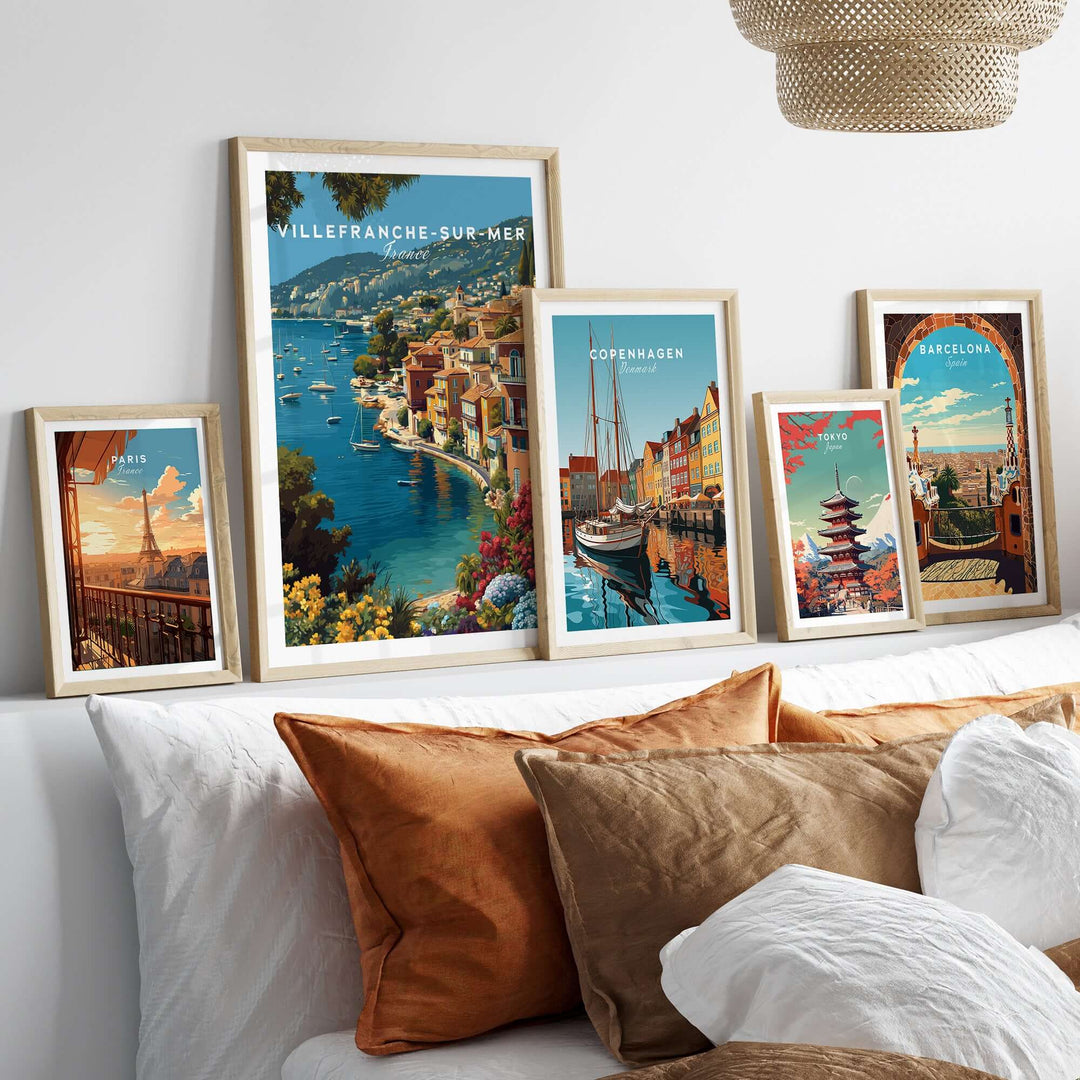 Gallery of framed travel posters featuring Villefranche-sur-Mer, Copenhagen, and Barcelona on a stylish couch.