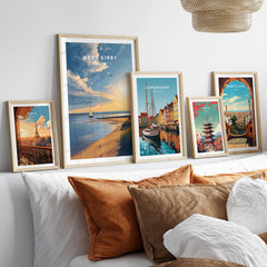 West Kirby England Travel Poster | Golden Sunset Beach Wall Art Print displayed among other travel posters on a cozy sofa.
