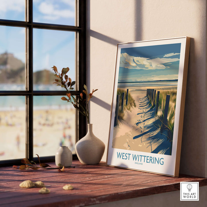 West Wittering Beach poster displayed on a wooden table by a window, showcasing Sussex's iconic coastline.