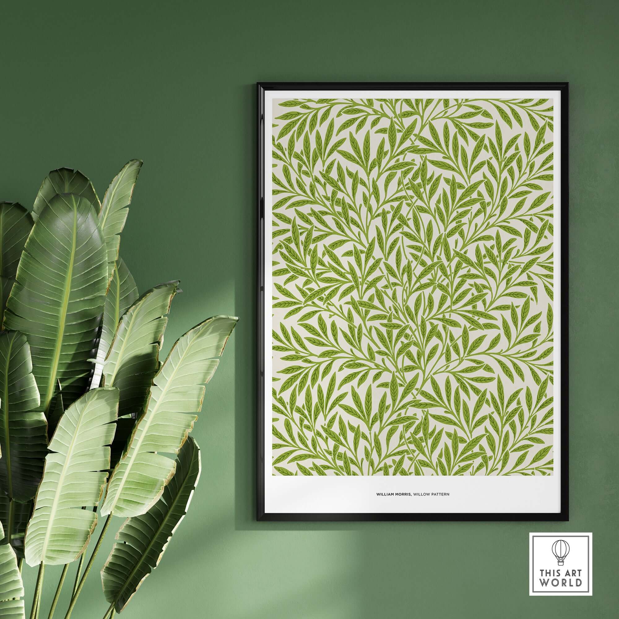 Exhibition Art Print William Morris Willow Pattern Green Botanical Wall Art displayed on green wall with plant.