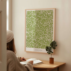Exhibition Art Print William Morris Willow Pattern Green Botanical Wall Art displayed on a wall with a person reading.