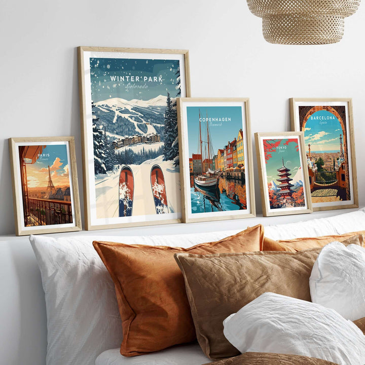 Collection of travel posters including Winter Park, Colorado, displayed on a bed with stylish decor and cozy pillows.