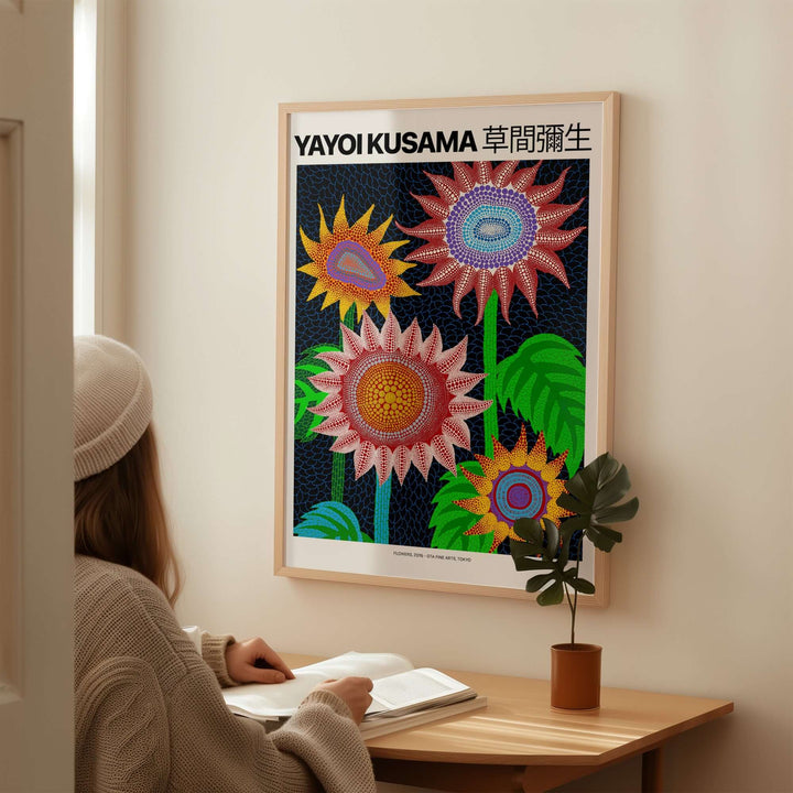 Yayoi Kusama colorful flowers art print poster on a wall, person admiring contemporary polka dot wall art in a cozy setting.
