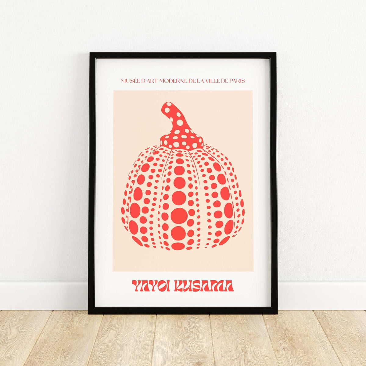 Yayoi Kusama Red Pumpkin Polka Dot Pop Art Print Poster Paris Exhibition Wall Art in a black frame on a wooden floor.