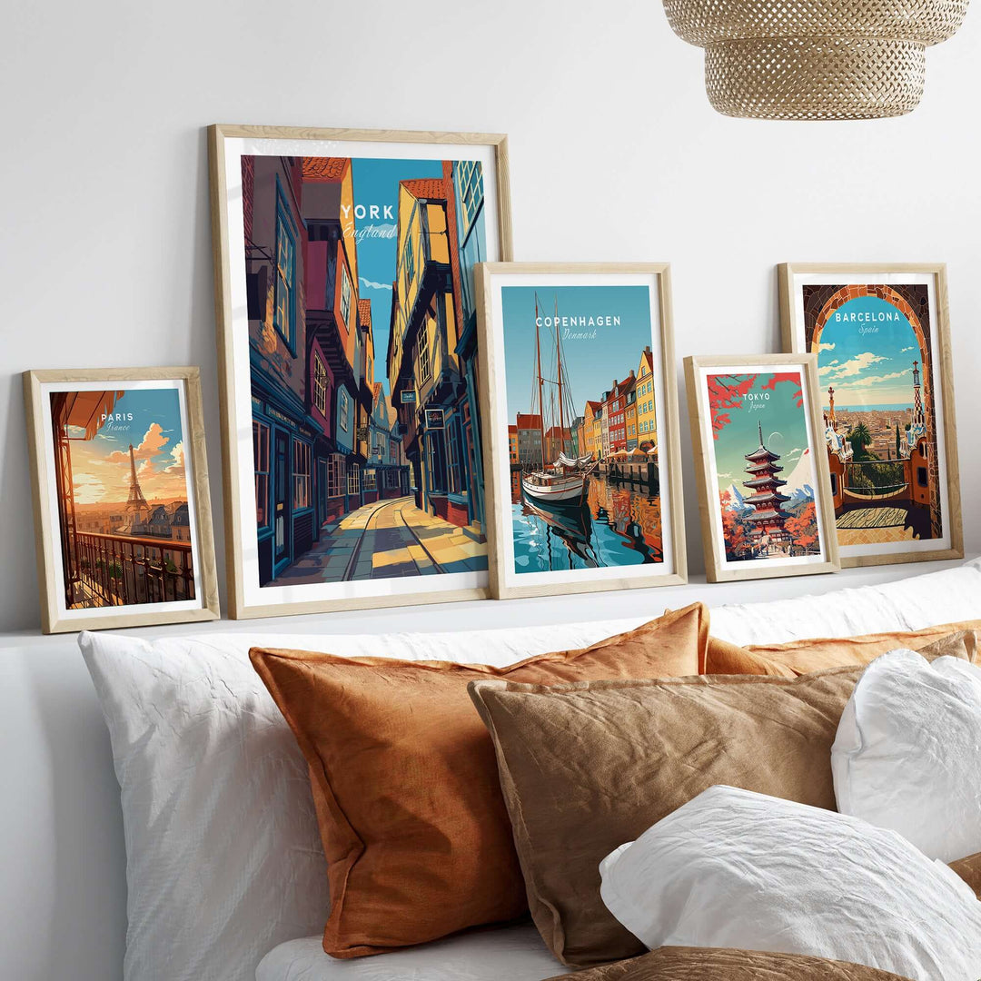 Framed posters of York, Copenhagen, and Barcelona displayed on a couch with decorative pillows.