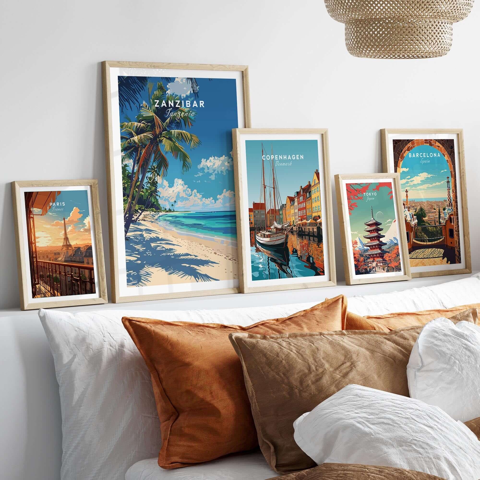 Zanzibar Print showcased among framed wall art on a bed, featuring vibrant tropical and cityscape designs.