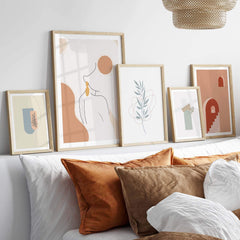 Modern palm leaf print wall art displayed above cozy pillows in a stylish living room setting.