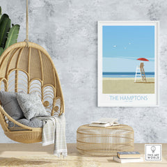 The Hamptons wall art print featuring a lifeguard stand and beach, styled in a cozy living space with hanging chair.