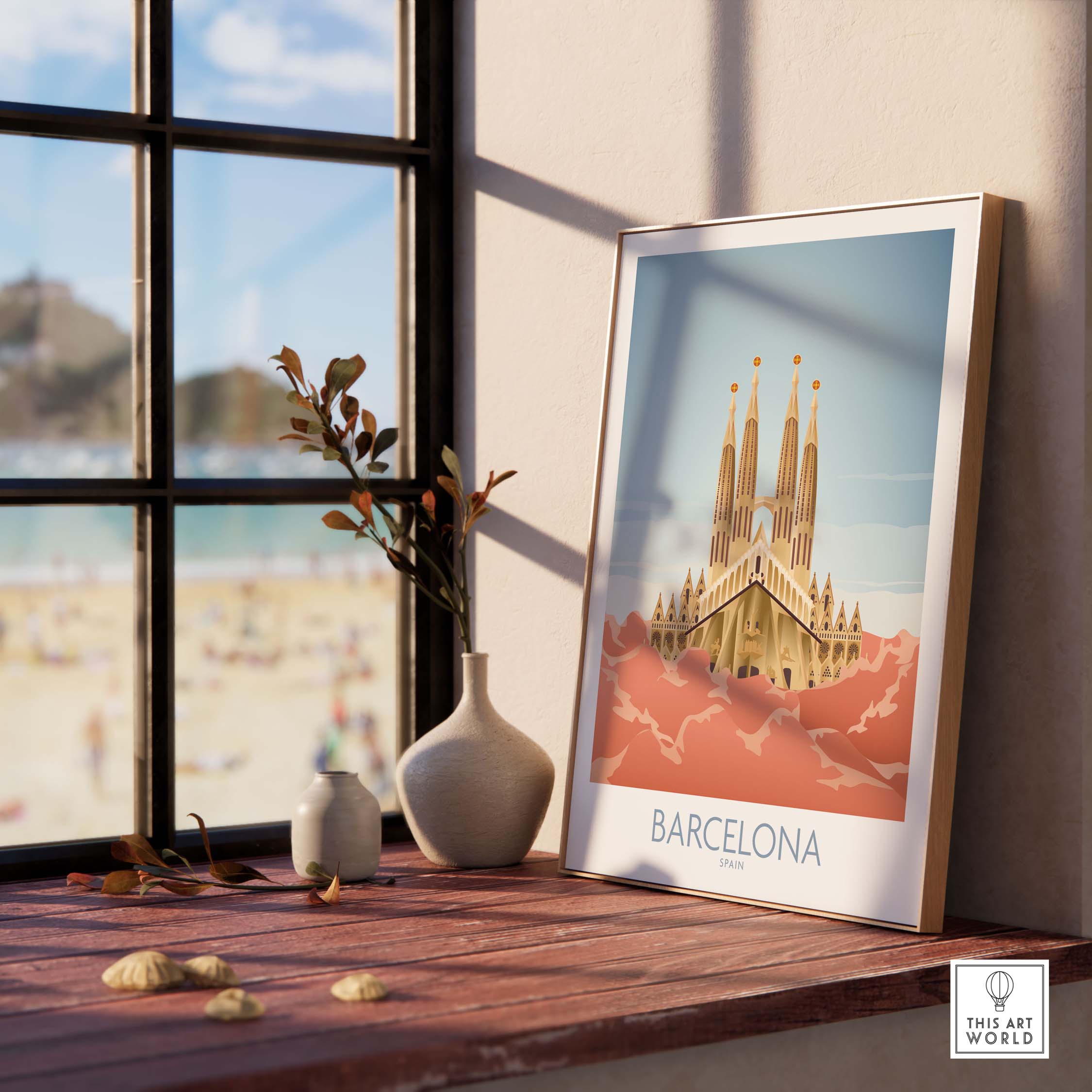 Barcelona wall art print featuring Sagrada Familia displayed on a shelf near a window with beach scenery.