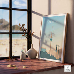 Berlin Print Wall Art Poster displayed on a wooden table with a view of the beach, featuring vintage-inspired design.