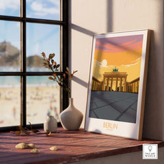 Berlin Print Germany Travel Poster displayed by a window, featuring the iconic Brandenburg Gate at sunset.