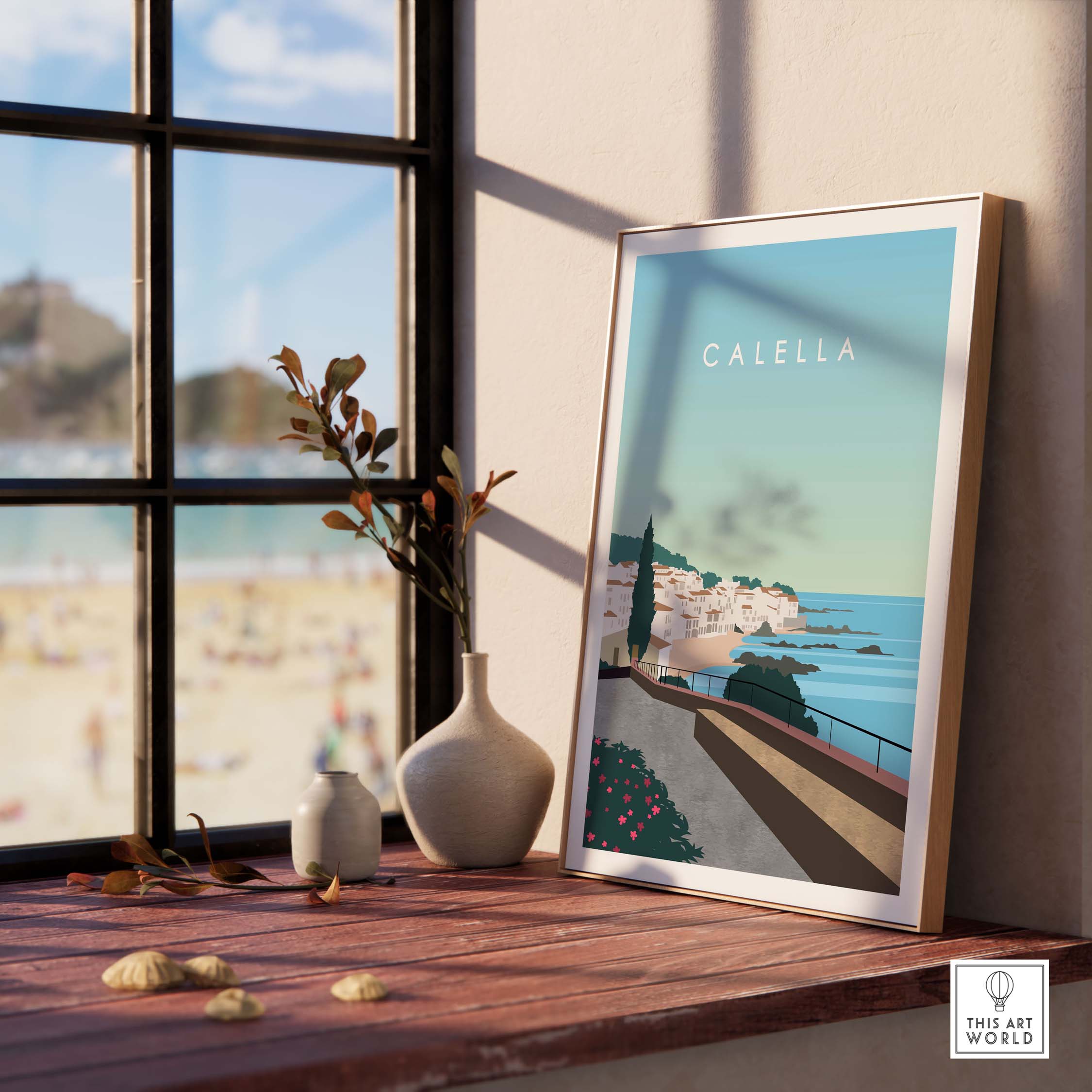 Calella Spain Print Poster displayed on a wooden table near a window with beach view.
