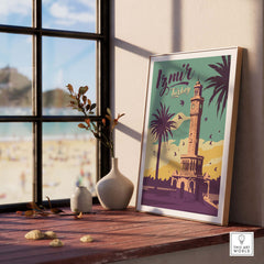 Izmir Print Turkey Travel Poster displayed on a wooden table with plants and a beach view in the background.