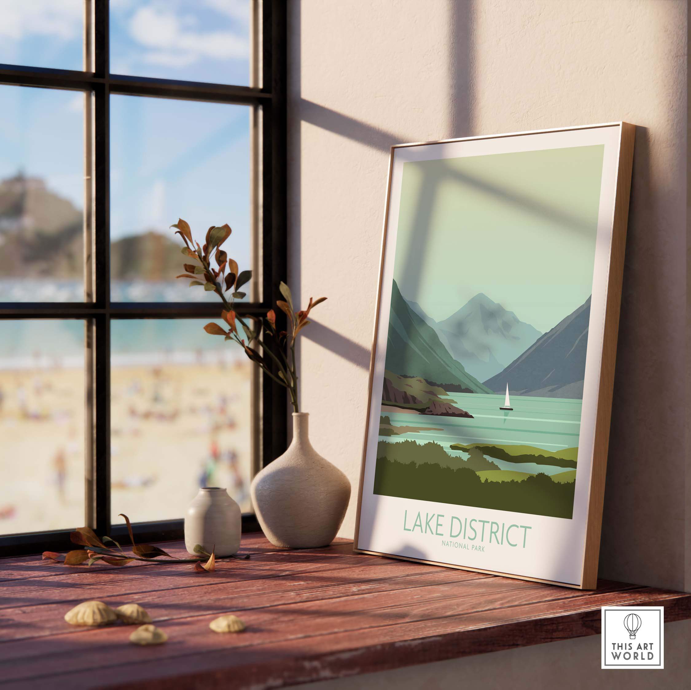 Lake District poster print framed on wooden table near window, showcasing scenic mountains and lake.