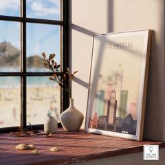 Los Angeles skyline poster displayed on a wooden table near a window, featuring colorful city buildings and beach view.