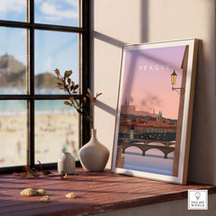 Framed Prague Print Wall Art Poster on table with sunset view, perfect for home decor and travel enthusiasts.