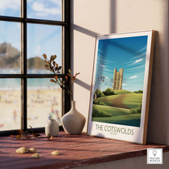 A framed Cotswolds print depicting a scenic landscape and vintage travel art inside a stylish home setting.
