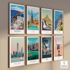 Collection of framed travel posters featuring Santorini, Seville, Iceland, Postano, New York, Amsterdam, Paris, and Lisbon.