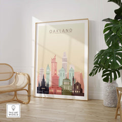 Oakland skyline wall art print in warm pastels, framed in a stylish interior setting with plants.