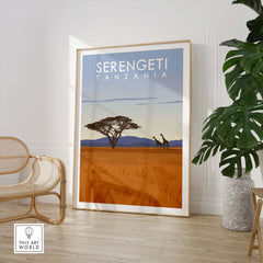Serengeti Print Tanzania travel poster displayed in a stylish interior setting with a chair and plant.