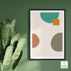 Abstract digital print featuring geometric shapes, displayed in a modern room with green walls and indoor plants.