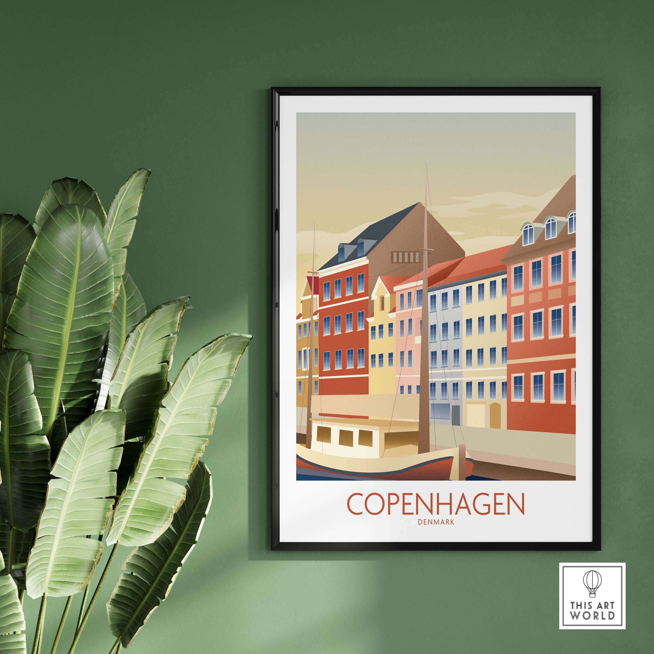Framed Copenhagen Wall Art print featuring colorful buildings and a boat on a serene waterfront, styled with greenery.