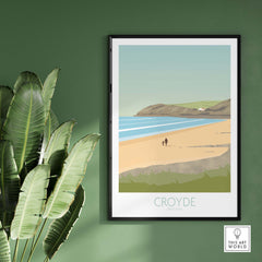 Croyde Beach Print framed on a green wall, showcasing a serene beach scene in Devon, England.