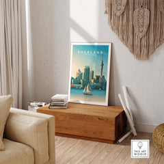 Auckland travel poster print displayed in a stylish living room, featuring vintage-inspired art with city skyline and sailboat.