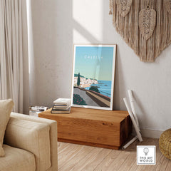 Calella Spain print poster showcased in a stylish living room with natural decor and soft furnishings.