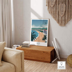 Nice France travel poster displayed in a stylish living room, featuring a beach and palm trees.