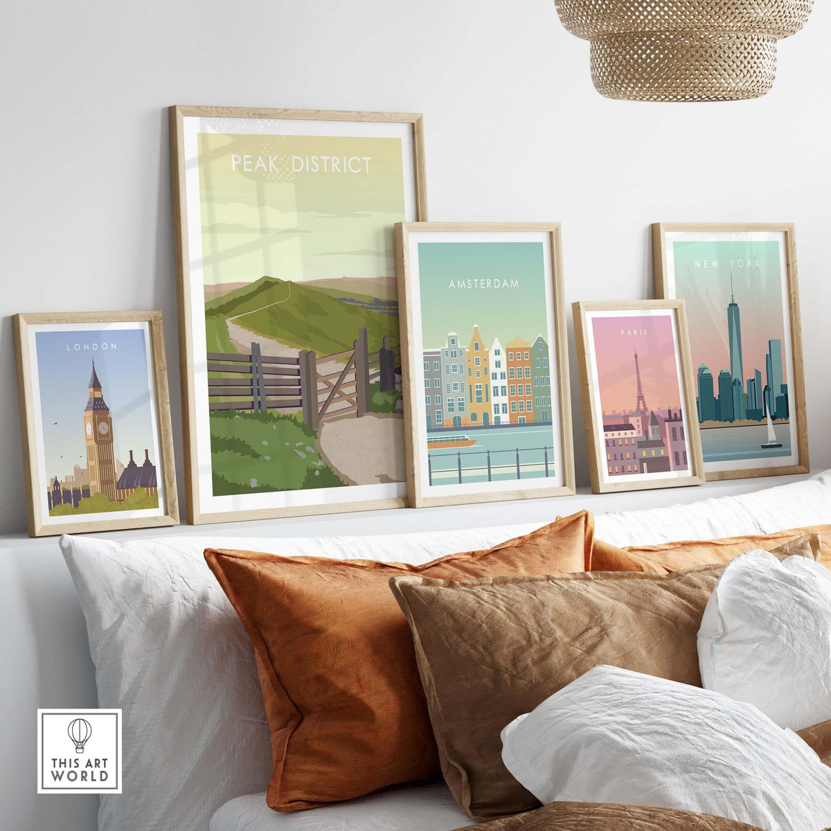 Framed travel posters including Peak District, London, Amsterdam, and Paris displayed on a stylish sofa.