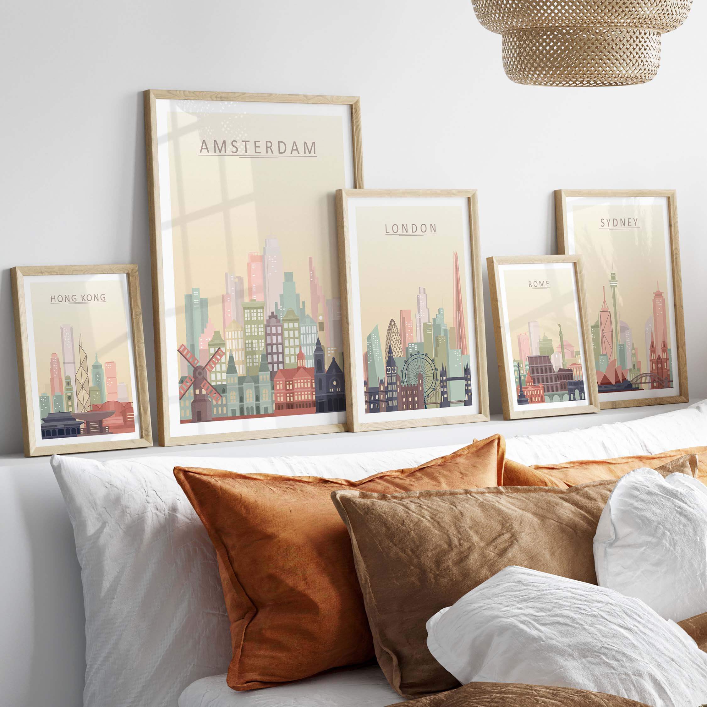 Amsterdam skyline print wall art displayed with other city prints on a wall above a bed with decorative pillows.