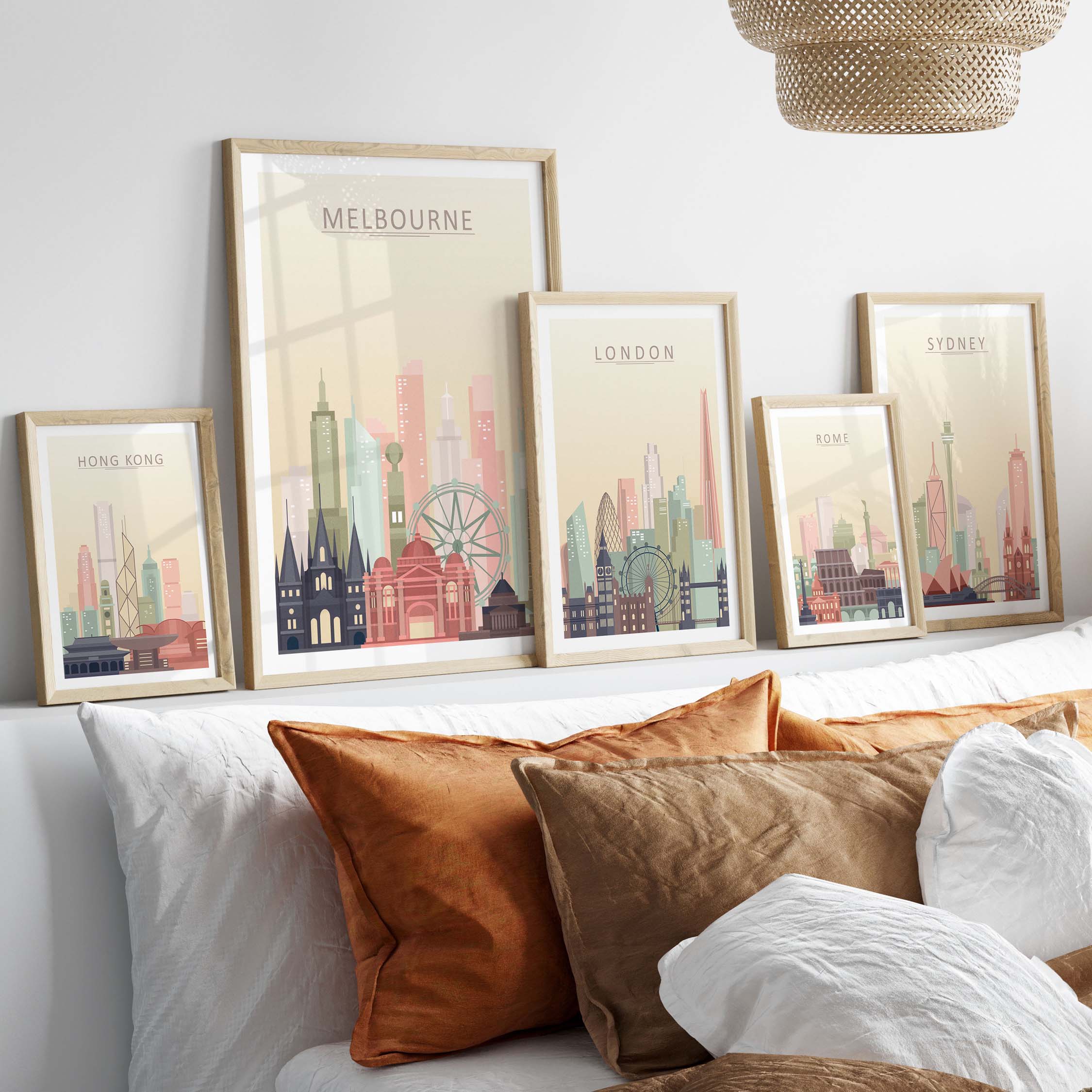 Framed city skyline prints of Melbourne, London, Sydney, and Hong Kong with warm pastel tones on a stylish wall.