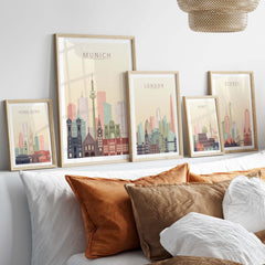 Artistic display of city skyline prints featuring Munich, London, Sydney, and Hong Kong in warm pastel tones.