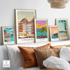 Framed vintage travel art prints featuring Copenhagen, Lake Como, San Juan, Maui, and Amalfi Coast on a stylish shelf.