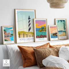 Framed North Carolina wall art print displayed among other vintage travel posters on a sofa.