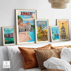 Amalfi Coast vintage poster art displayed with other city prints on a cozy wall above a sofa.