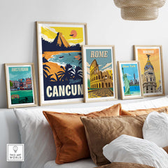 Framed vintage travel posters, including Cancun, Amsterdam, Rome, and New York, displayed on a stylish sofa.
