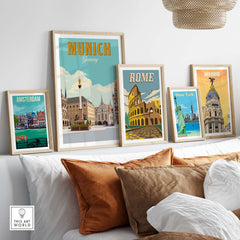 Munich Germany print displayed with framed travel posters of Amsterdam, Rome, and Madrid on a cozy sofa.