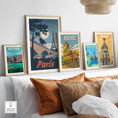 Paris poster wall art print displayed among framed travel prints of Amsterdam, Rome, New York, and Madrid on a stylish sofa.