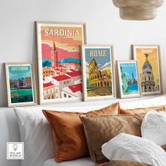 Sardinia Poster Print among framed travel posters of Amsterdam, Rome, and Madrid on a modern living room couch.