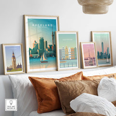 Auckland travel poster print among other city prints on a stylish couch, showcasing minimalist wall art decor.