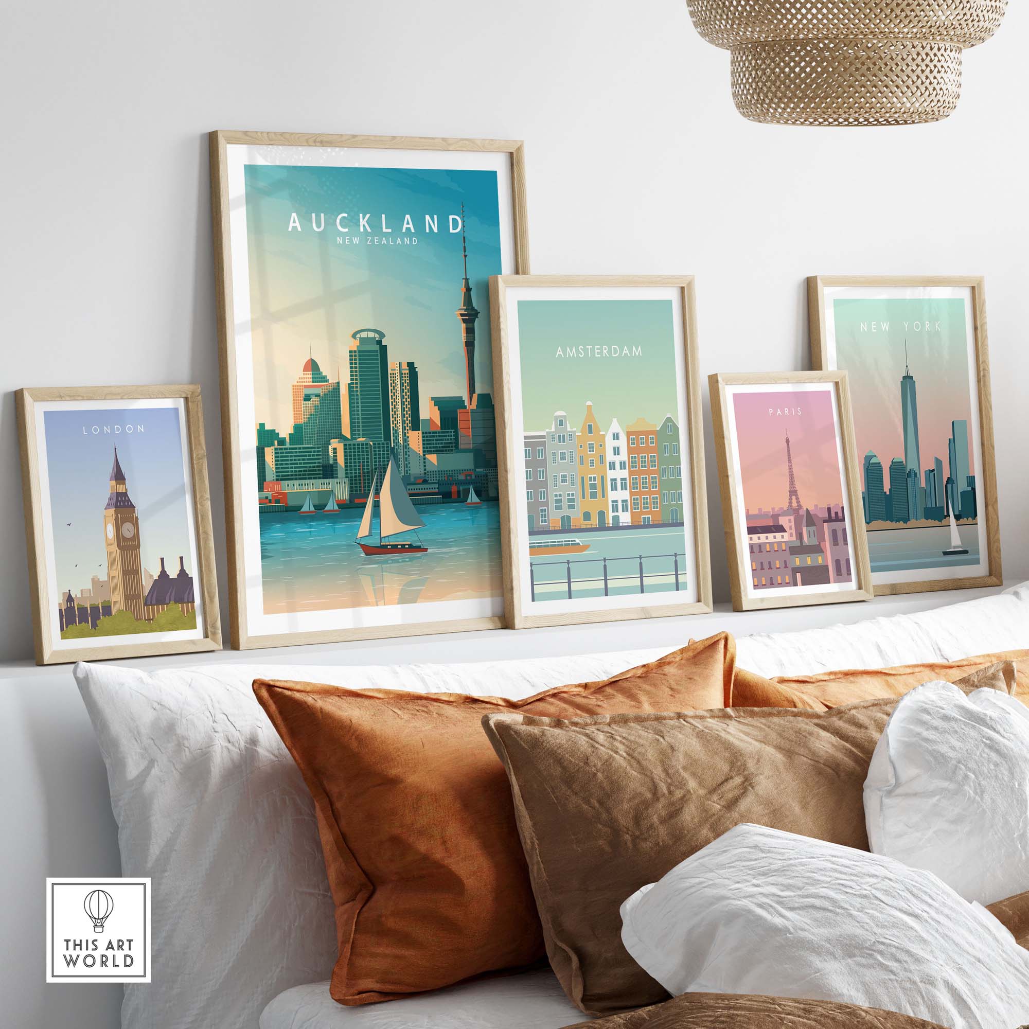 Auckland travel poster print among other city prints on a stylish couch, showcasing minimalist wall art decor.