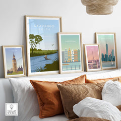 Gallery of vintage travel posters including Okavango Delta, London, Amsterdam, and Paris prints on a stylish sofa.