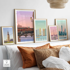 Framed travel wall art featuring iconic city prints of London, Amsterdam, New York, and Prague in a cozy living room setting.