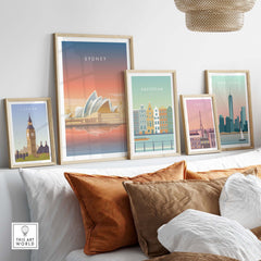 Framed Sydney wall art poster among other city posters on a cozy sofa with decorative cushions.