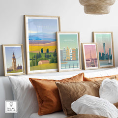 Framed Tuscany Italy Wall Art Poster among other city posters on a stylish sofa, showcasing travel-inspired decor.