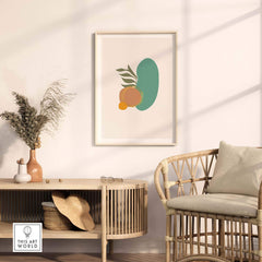 Mid Century wall art with abstract shapes featuring a green form and orange fruit in a stylish living room setup.