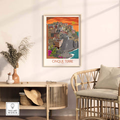Cinque Terre print framed on a wall above a stylish rattan chair and table, showcasing vintage travel art.