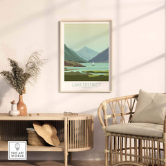 Lake District poster print displayed in a cozy interior setting, featuring vintage travel art of mountains and a sailboat.